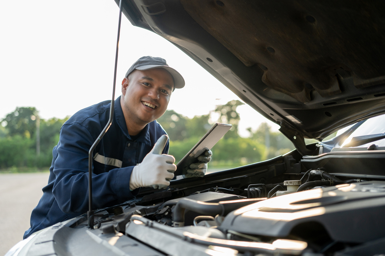 Professional car mechanic maintenance vehicle. The mechanic opens the front of the car. Checking the broken engine. Check the damage as listed. Repair car outside service. New-England-Uniform-Truck