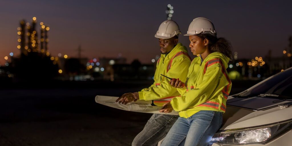 high visibility work wear uniforms at night working in new england sitting at the hood of a car